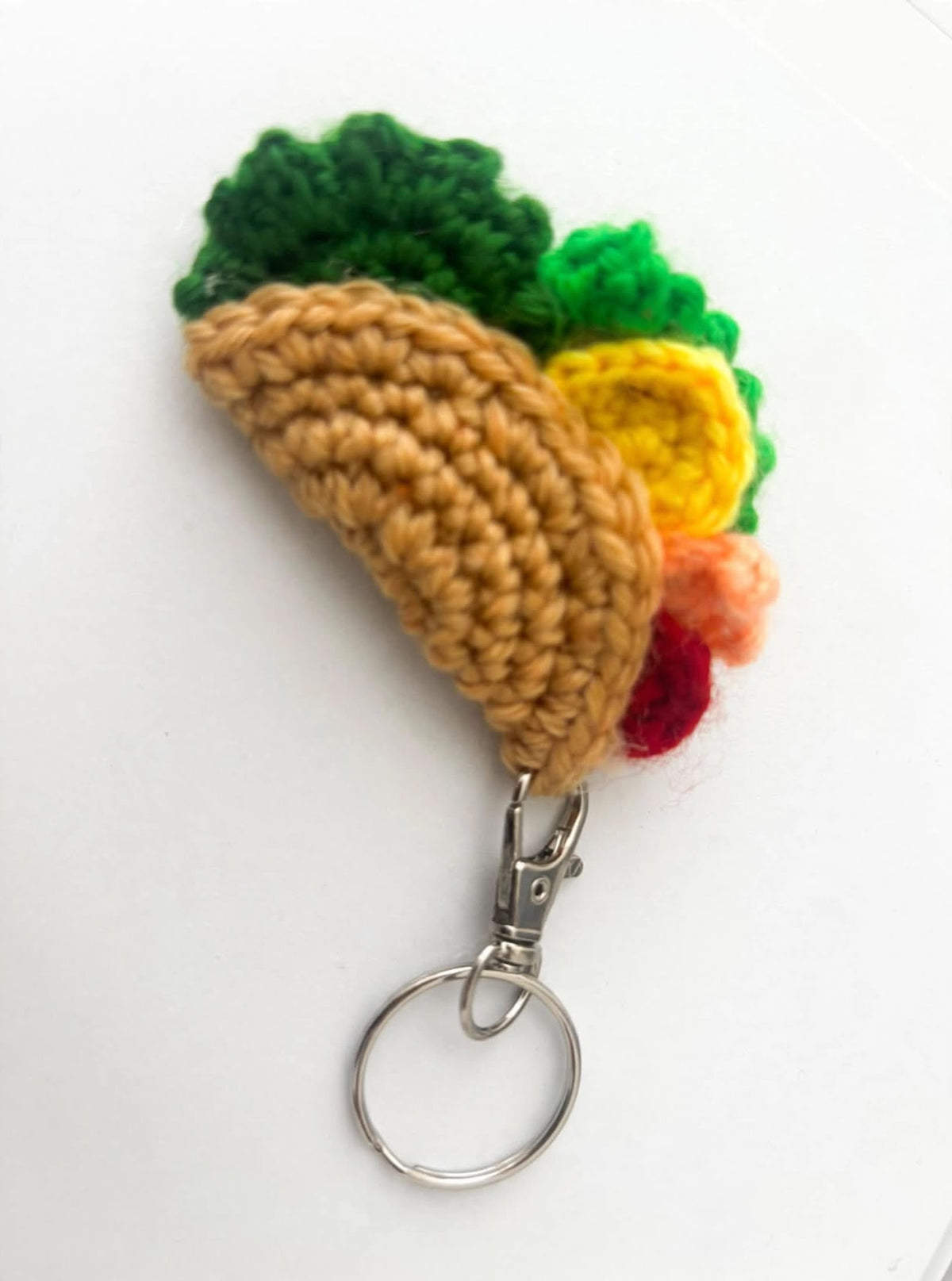 Handmade crochet taco keychain with golden shell, green lettuce, yellow cheese and red tomato on silver keyring